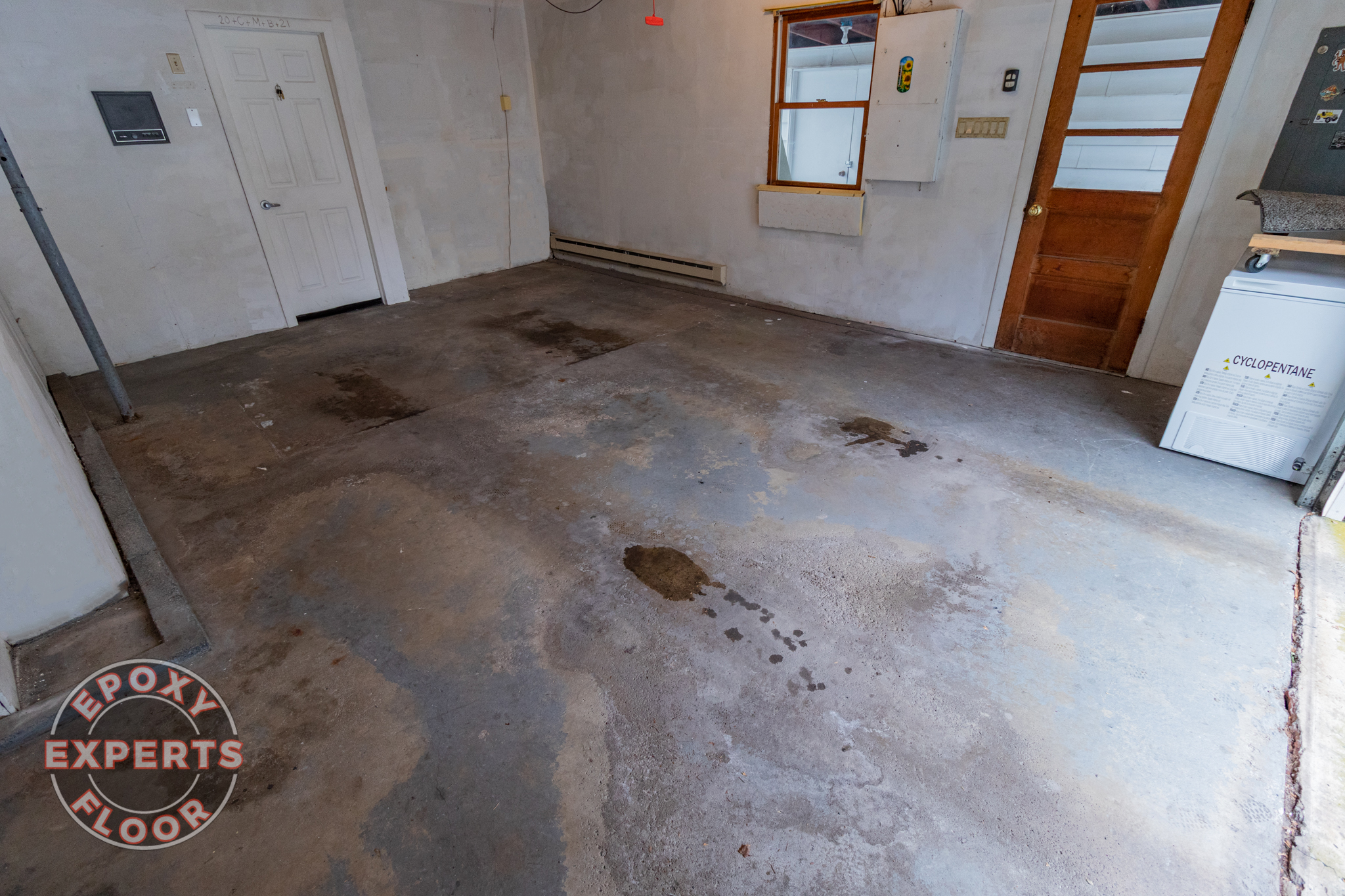 Concrete on garage with visible damage from use before epoxy floor experts repair